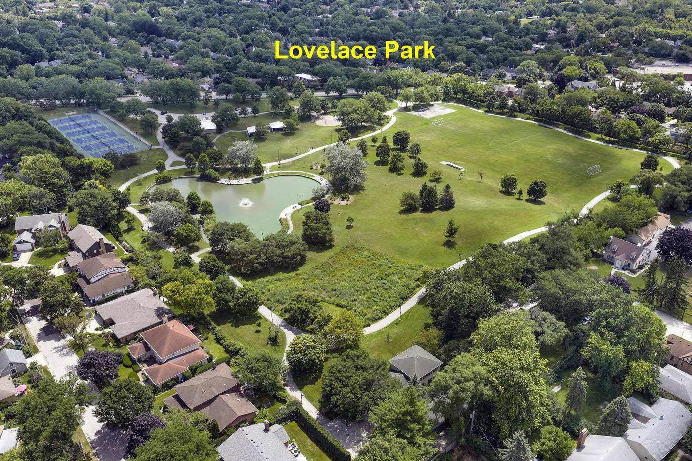 Aerial view of Lovelace Park in Wilmette showing the stocked pond and fountain, tennis courts, playfields and walking paths