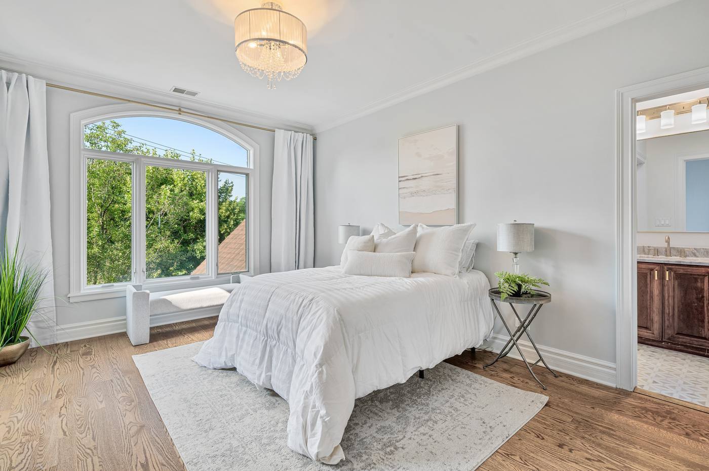 Bedroom with arched window and window seat, opening to an en-suite bath