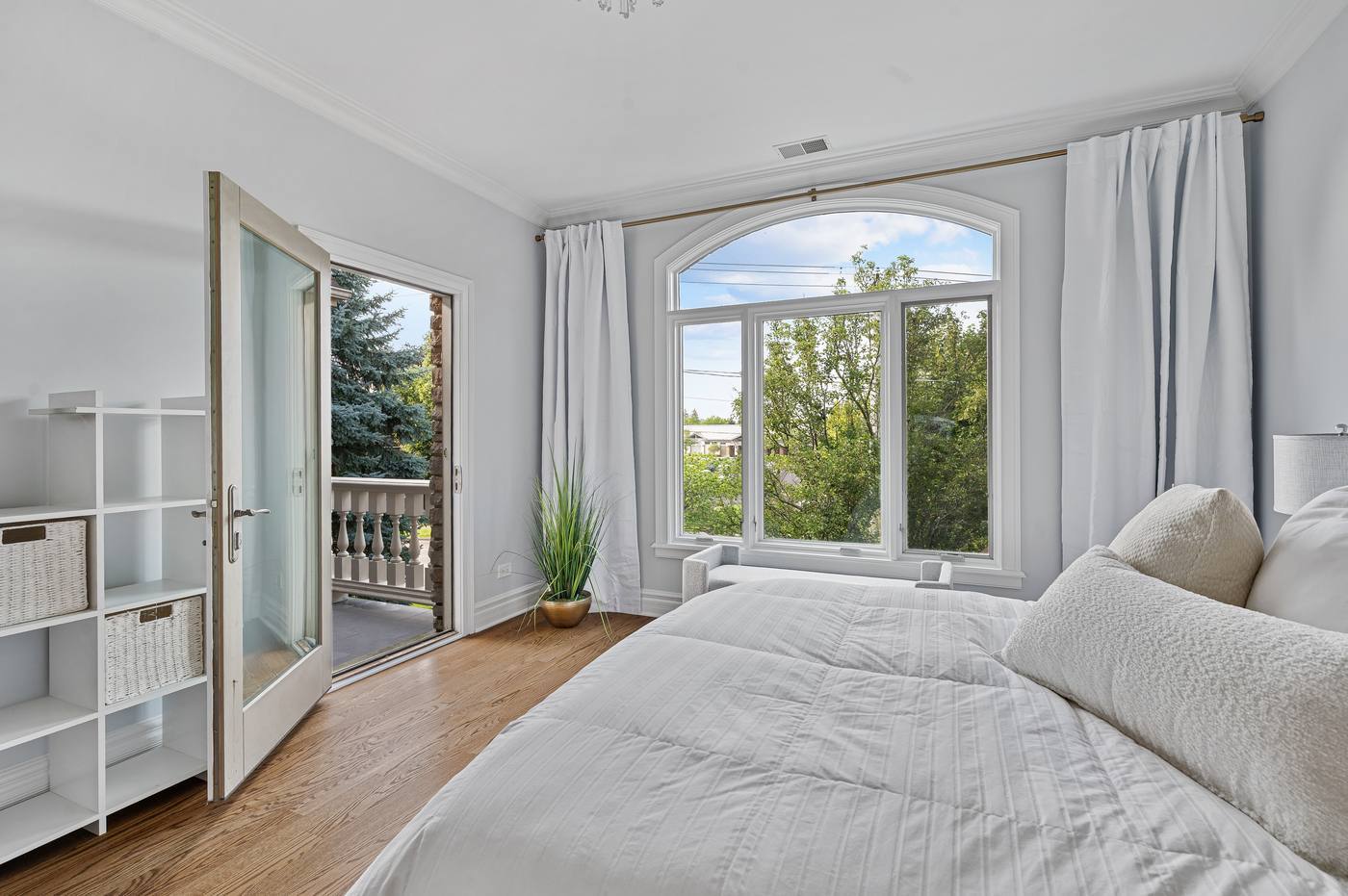 Bedroom with a French door to its own balcony and an arched window