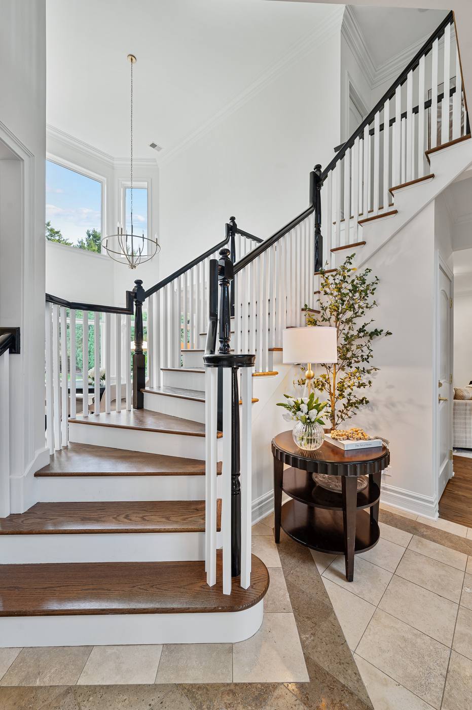 Curved staircase rising from the stone-floored foyer, two stories of light above