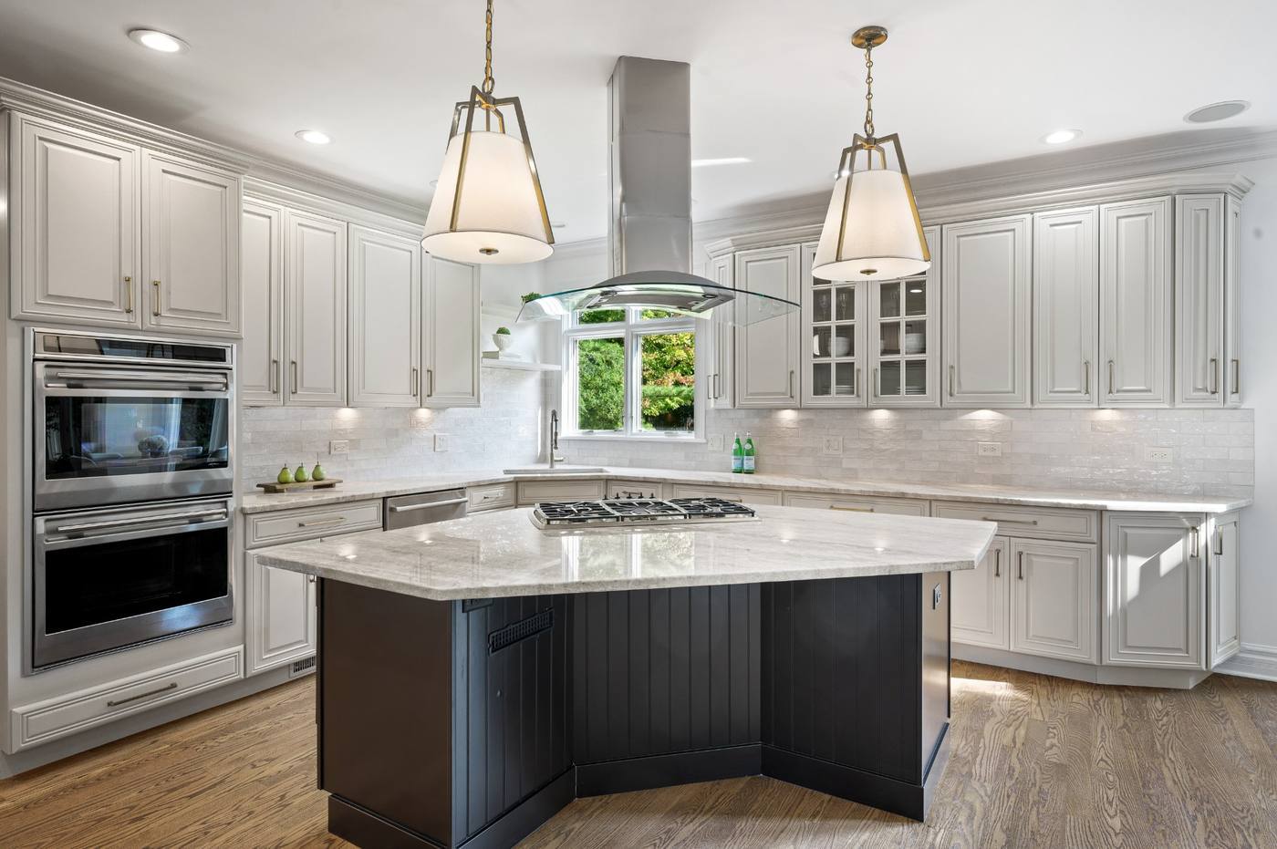 Kitchen with center island, quartzite counters, double ovens and glass hood