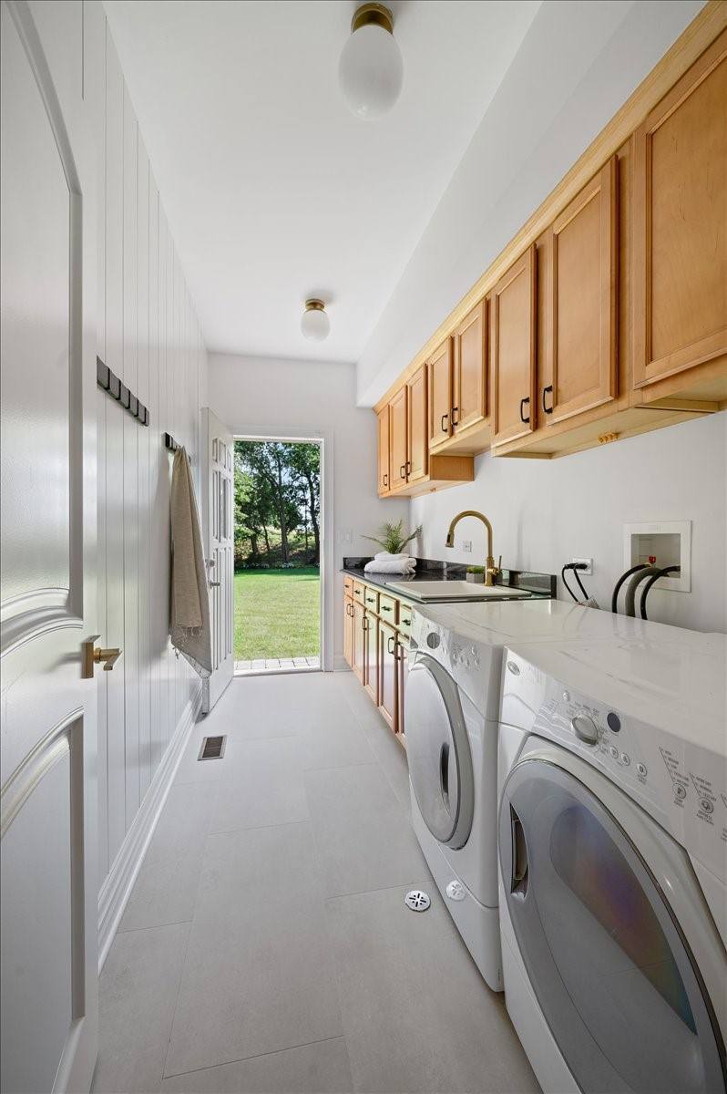 Laundry and mudroom off the garage, with sink, cabinetry and a door to the yard