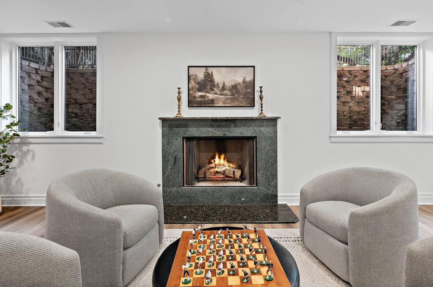 Lower-level fireplace in green marble, flanked by two above-grade windows