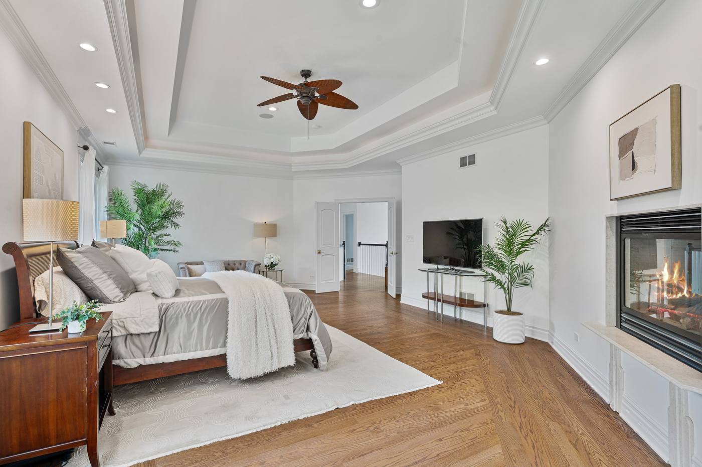 Primary bedroom with tray ceiling, gas fireplace and double doors to the landing