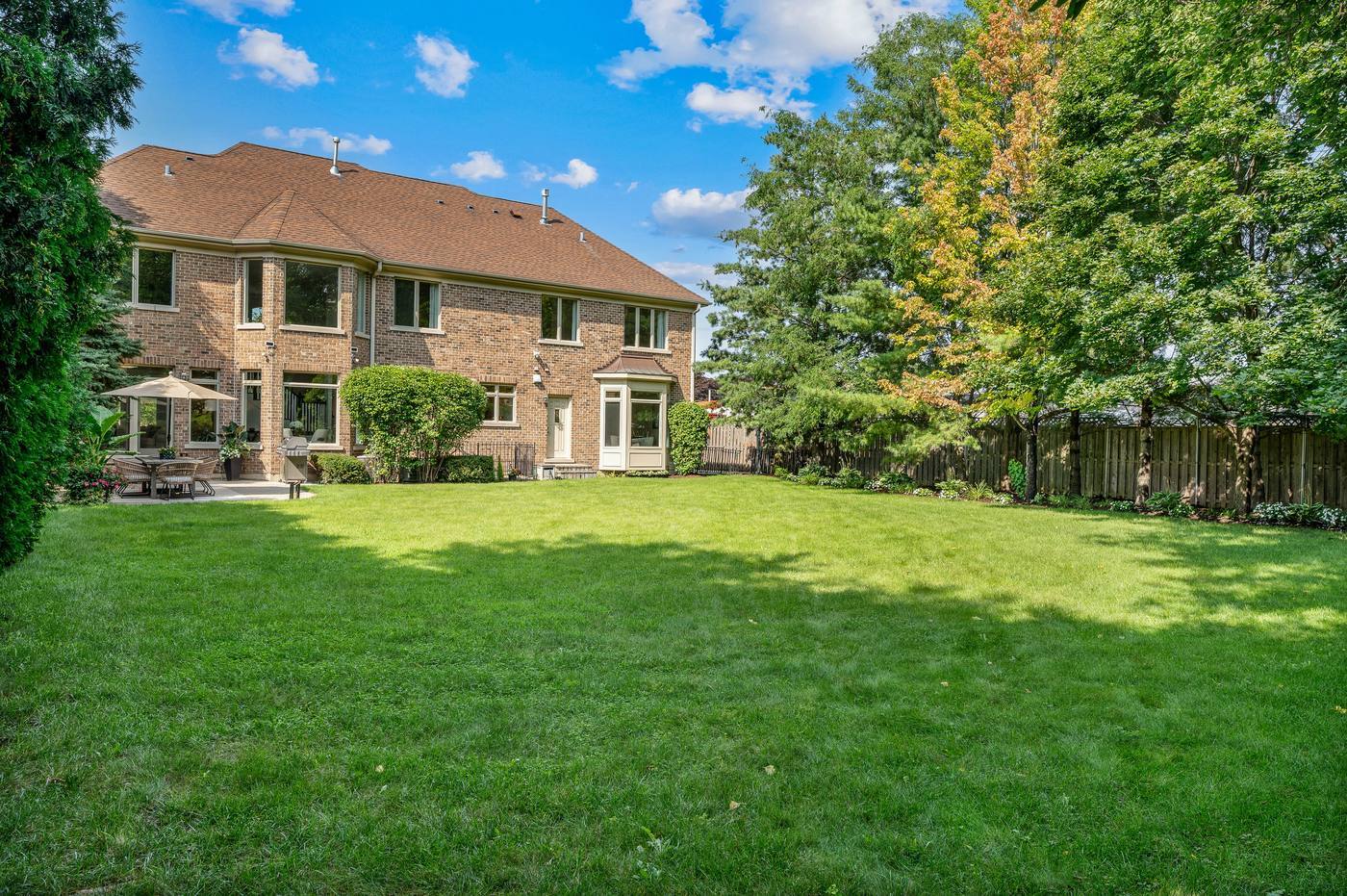 Rear elevation from across the lawn — the patio, the bay and the depth of the yard