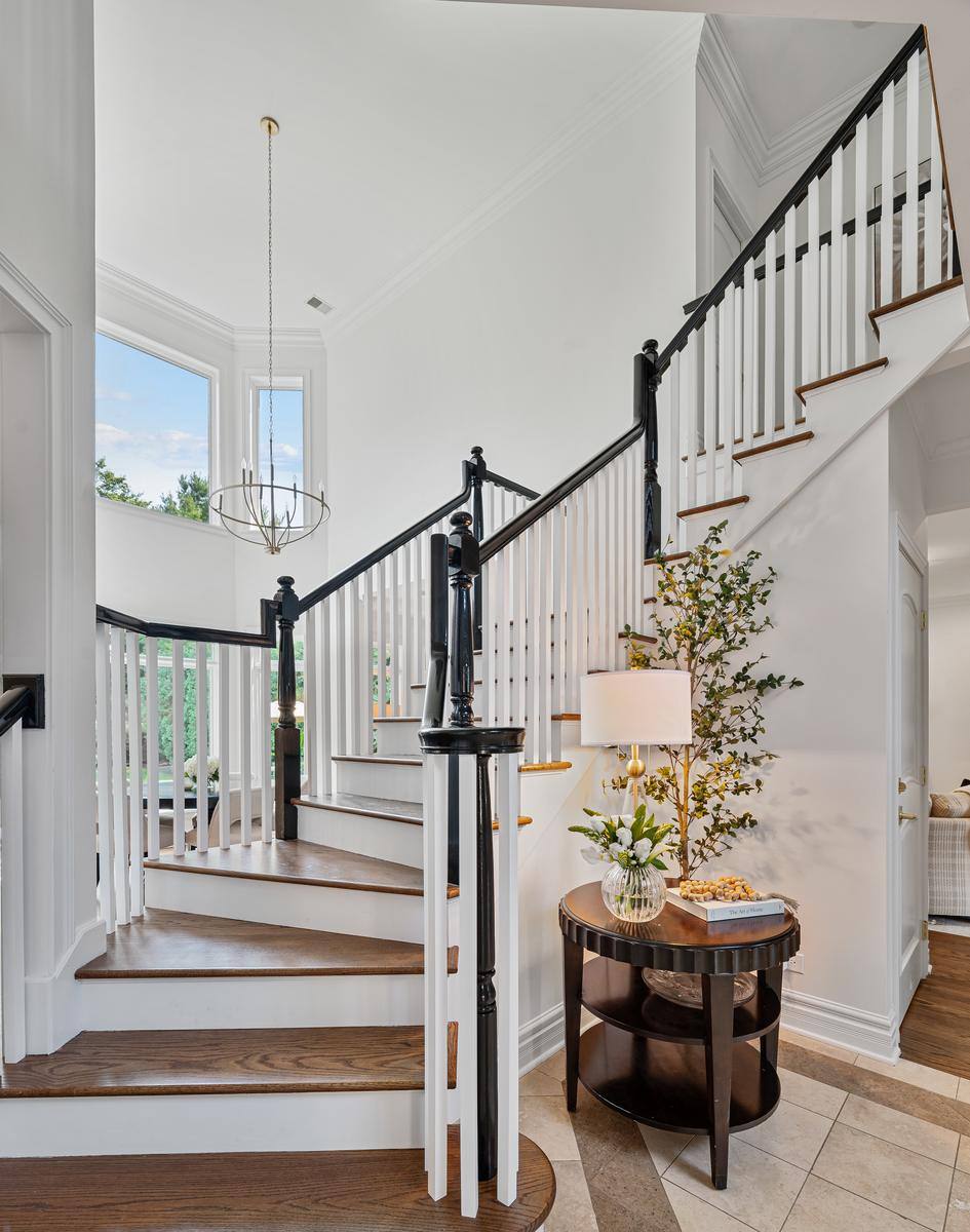 Two-storey stair hall at 2303 Old Glenview Road, with the curved staircase, chandelier and windows on two levels